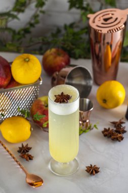 Ekşi kokteyl bir barın üzerinde duruyor. Arkasında bir kokteyl makinesi ve elmalar var.