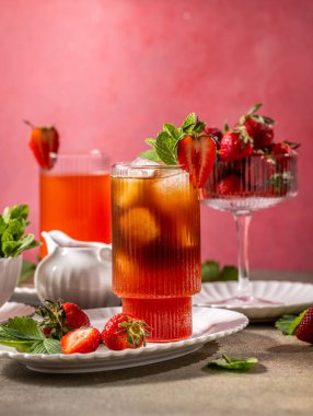 Refreshing summer drink of iced tea is garnished with fresh strawberries and mint leaves clipart