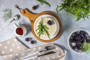 Tahtada böğürtlen ve roket salatası ile taze yuvarlak peynirin üst görüntüsü, böğürtlen sosu ile servis edilir, sağlıklı yeme kavramı
