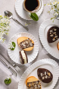 Çikolata ve bademle süslenmiş lezzetli paskalya yumurtası şekilli kurabiyeler kahve ve çiçeklerle servis edilir.