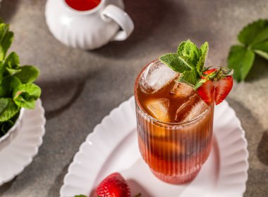 Taze nane ve buz küpleriyle süslenmiş, beyaz bir tabakta zarif bir bardakta servis edilen çilekli buzlu çayı tazeliyorum.