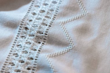 Beyaz dantel kurdelenin yakın plan çekimi beyaz keten kumaşı geliştirir, ince işçilik ve tekstil dokuları sergiler.