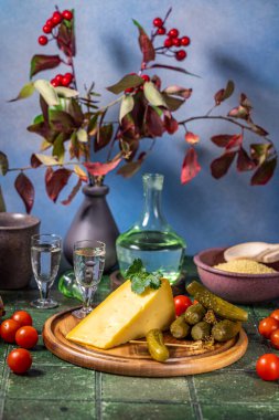 Tahta bir tahtanın üzerinde votka, peynir, turşu ve domatesli geleneksel Rus aperatifi.