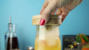 Yetenekli barmen, canlı turuncu renkte dumanlı tropikal kokteyli ortaya çıkardı. Zarif bir içeceğe hazırlanırken, derin mavi arka planda baştan çıkarıcı bir koku yaydı.