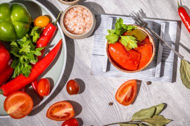 Lezzetli kırmızı çan biberleri taze domates, kırmızı biber, bitkiler ve baharatlarla servis edilir, canlı ve lezzetli bir mutfak sahnesi yaratır.