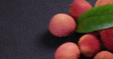 Olgun, parlak lychees canlı yeşil yaprak nazikçe dinlenen parlak siyah yüzey, tropikal meyve doğal güzellik ve tazelik göstermektedir