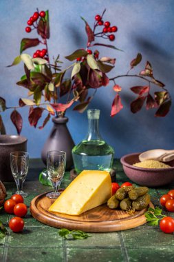 İçinde turşu, vişneli domates ve iki küçük bardaktan oluşan tahta bir tahtanın üzerindeki peynirin olduğu sakin bir hayat.