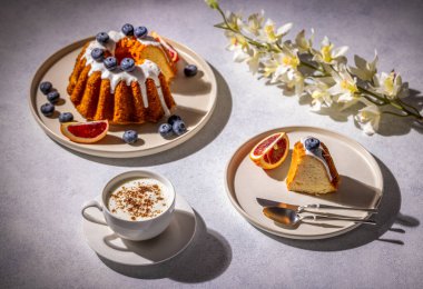 Yabanmersinli ve portakal dilimli Gugelhupf keki kapuçinoyla servis edilir ve orkide çiçekleriyle süslenir, samimi ve davetkar bir atmosfer yaratır.