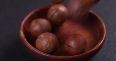 Macadamia fındıkları yumuşak bir şekilde kırsal ahşap bir damara dönüşerek gölgeli yüzeyde sağlıklı besin özelliklerini ön plana çıkarıyor.