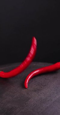 Kırmızı biberler karanlık bir yüzeye düşerek görsel olarak çekici bir dizi oluştururlar.