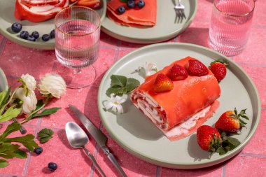 Kremalı çilekli krep ve pembe bir masada servis edilen taze çilekli pasta, tadını çıkarmaya hazır.