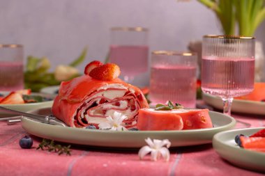 Krem şantili pembe çilekli pasta, taze çilek, yabanmersini ve yasemin çiçekleri yeşil bir tabakta sunulmaya hazır, tadını çıkarmaya hazır.