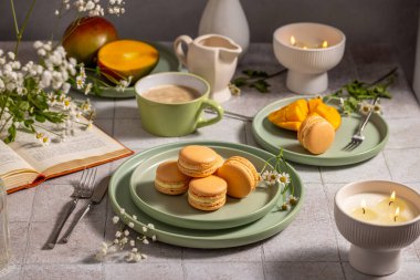 Tabakta narin mango makaronları, kahve, taze mango dilimleri, açık bir kitap ve mumlarla eşleştirilir, rahat bir atmosfer yaratır.