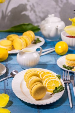 Taze limon dilimleri ve nane şekeriyle servis edilen parlak sarı limonlu kurabiyeler ferahlatıcı bir yaz tatlı sahnesi yaratıyor.