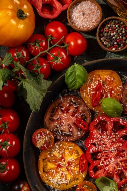 Renkli olgun domates dilimleri, rendelenmiş peynir, taze fesleğen yaprakları, ve bir tutam biber, tuz ve biber, canlı bir aşçılık başyapıtı oluşturur.