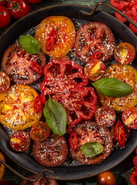 rengarenk peynirli, biberli ve fesleğenli domatesler, rengarenk metal bir tavada canlı ve iştah açıcı bir sunum yaratıyor.