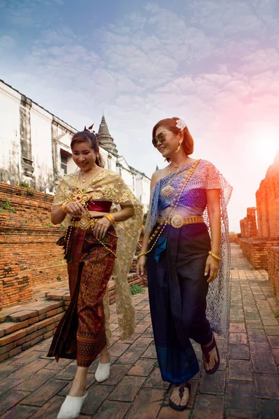タイのユネスコ世界遺産の1つアユタヤ寺院を歩く古いタイの伝統的なスーツを着た2人のアジア人女性 — ストック写真