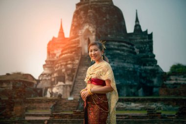 Tayland geleneği elbisesi giyen güzel Asyalı kadın mutlulukla gülümsüyor Ayutthaya 'da Bangkok thailand yakınlarındaki Unesco' nun dünya mirası alanında yaşlı stupa 'ya karşı duruyor.