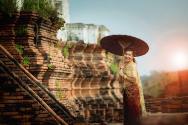 Elinde bambu şemsiyesi tutan Asyalı kadın Tayland 'ın merkezindeki Ayutthaya Dünya Mirası tapınağında duruyor.