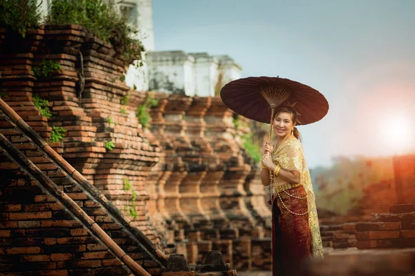 タイのユネスコ世界遺産に登録されているアユタヤの古い寺院に竹の傘を持っているアジアの女性 — ストック写真