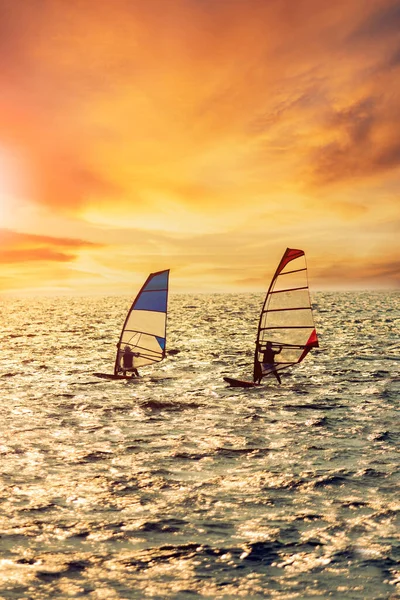 Два Человека Играют Виндсерфинг Над Стремительным Морем Против Красивого Освещения — стоковое фото