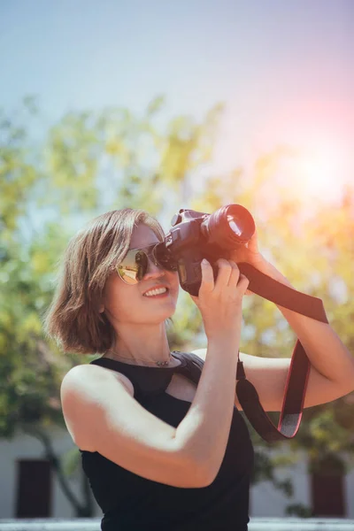 Stock image asian woman taking a photo with dslr camera standing outdoor against beautiful sun light