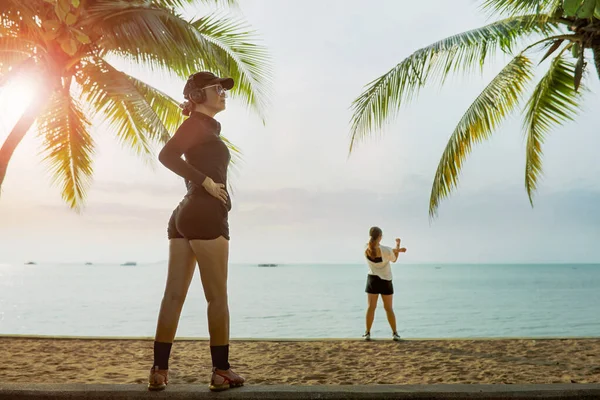 Δύο Γυναίκες Που Τεντώνονται Πριν Από Την Άσκηση Στην Παραλία — Φωτογραφία Αρχείου