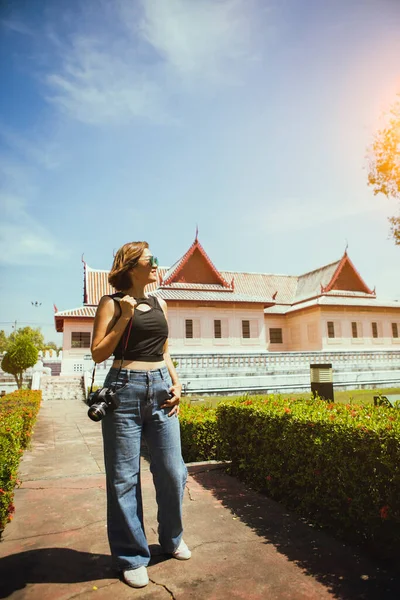 タイ文化の建物のスタイルで屋外に立ってDslrカメラを保持する女性 — ストック写真