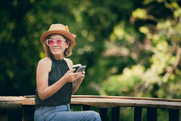 Mooie Aziatische Vrouw Holdin Smartphone Kopje Koffie Zitten Thuis Terras — Stockfoto