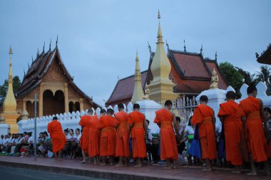 Luang prabang laos - 22 Haziran 2023: Köylü ve turist, Luang Prabang 'ın en ünlü şehir simgesi olan Wat sensoukharam' da sabah erken saatlerde Budist keşişe yapışkan pirinç sunuyorlar.