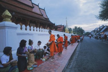 Luang prabang laos - 20 Haziran 2023: Köylü ve turist, Luang Prabang 'ın en ünlü şehir simgesi olan Wat sensoukharam' da sabah erken saatlerde Budist keşişe yapışkan pirinç sunuyorlar.