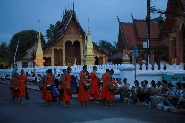  Lao keşişi Luangprabang caddesindeki Asyalı kadından güzel Wat Sensoukharam Tapınağı çitlerine karşı pirinç ve yiyecek alıyor. 