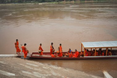 Luangprabang-19,2023: Laos 'un kuzeyindeki Maekong nehrinin yanındaki Wat xiang tanga tapınağında keşiş ve evcil tekne.