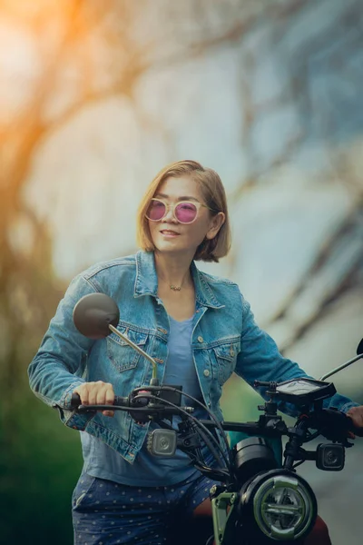 漂亮的女人在自然轨道上骑摩托车 免版税图库图片