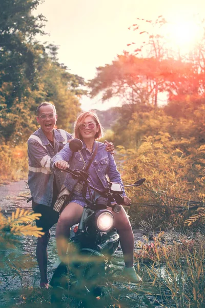 亚洲夫妇在丛林小径上骑摩托车快乐 图库图片