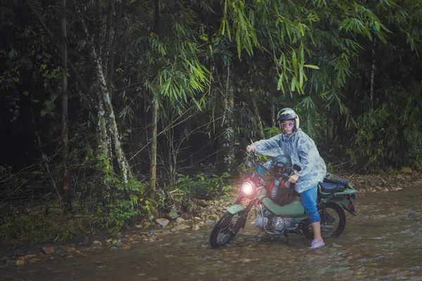 漂亮的女人骑着小摩托车穿过浅浅的小溪 — 图库照片