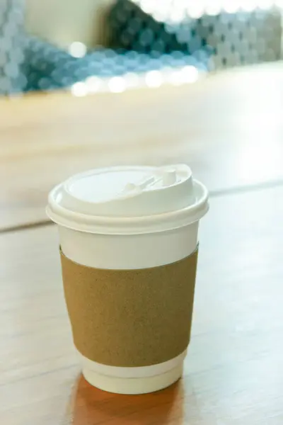 茶色のペーパーによる熱いコーヒー カップ カバーは木製のテーブルの熱温度を保護します ストック画像