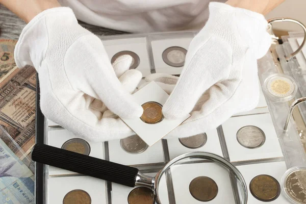 手拿着不同的旧硬币和装有放大镜的钞票 — 图库照片