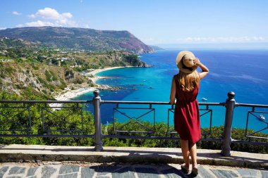 İtalya 'da turizm. Capo Vaticano 'da tanrıların kıyılarında şapkalı genç bir kadının panoramik manzarası, Calabria, İtalya.