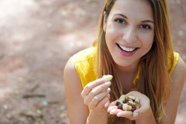 Healthy smiling girl eating a mix of nuts seed dried fruits looking at the camera. Copy space.