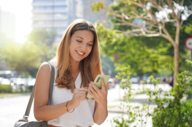 Brazilian business woman checking her mobile phone in Sao Paulo sustainable metropolis, Brazil
