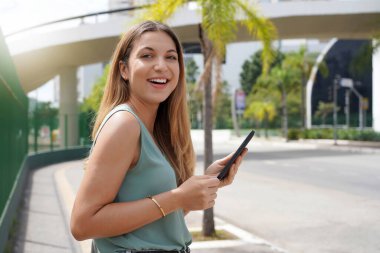 Young female entrepreneur walking in modern natural city in the morning
