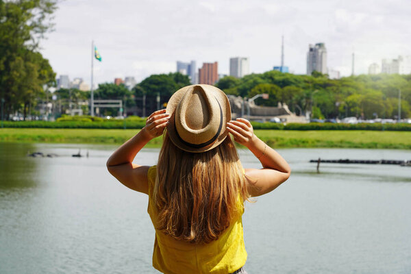 Tourism in Sao Paulo, Brazil. Back view of traveler girl enjoying skyline of Sao Paulo metropolis from Ibirapuera Park, Brazil.
