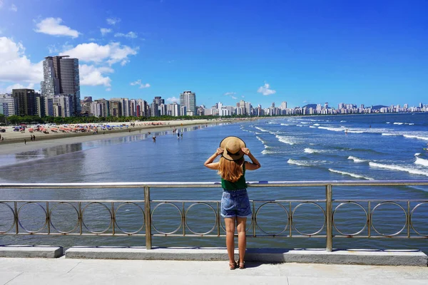 모자를 건물들의 스카이라인을 감상하며 브라질 파울로 산토스에서 대양을 흔드는 관광객 — 스톡 사진