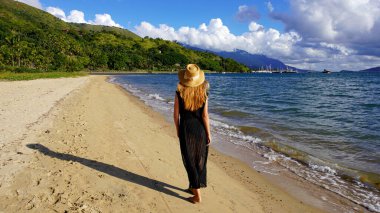 Brezilya, Ilhabela Adası 'nda gün batımında kumsalda yürüyen genç bir kadın.