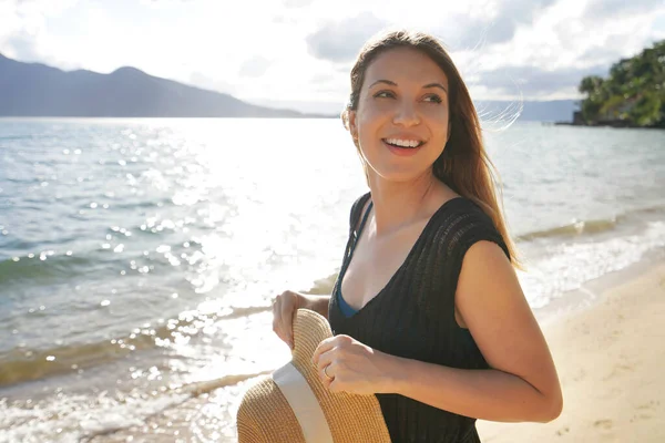 幸せな若い女性の肖像画は 太陽が熱帯の島の澄んだ海から反射し 日当たりの良いビーチでわら帽子を保持 — ストック写真