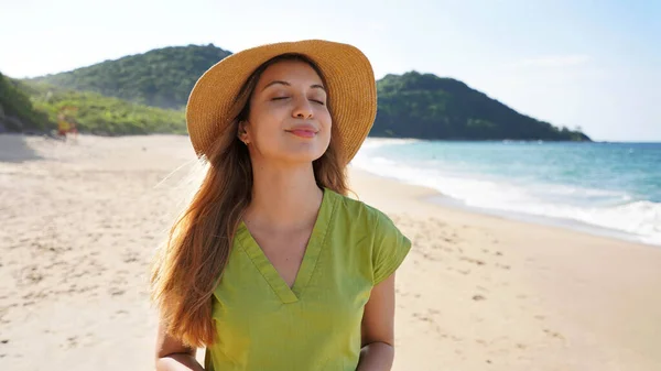 stock image Beautiful tourist woman with straw hat closes her eyes breathe relaxed with breeze on her face in summer vacation on the beach. Panoramic banner view. Summer vacation concept.