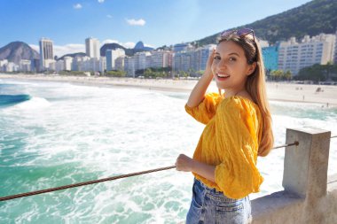 Copacabana Sahili, Rio de Janeiro, Brezilya 'nın dalgalı okyanus suyuyla şık, neşeli bir kızın portresi