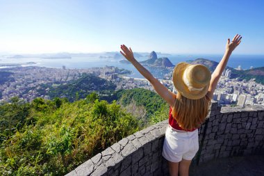 Brezilya, Rio de Janeiro 'da Guanabara Körfezi' nde Belvedere terasında kollarını kaldıran mutlu genç turist kadının hava manzarası.