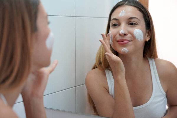 Beauty woman applying cream on her skin. Face moisturizing nourishing invigorating treatments. Enjoying relaxing time at home.